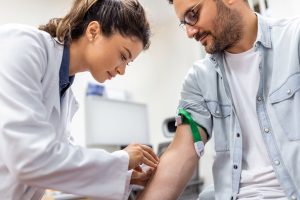 Friendly hospital phlebotomist collecting blood