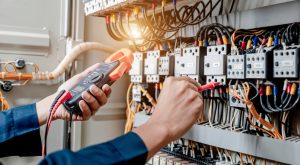 Electrician engineer uses a multimeter to test the electrical installation and power line current in an electrical system