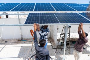 Workers installing solar panels on roof of house.